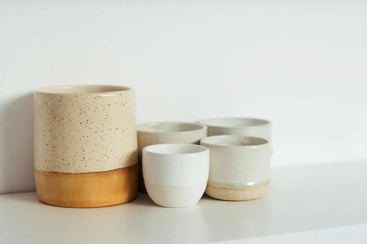 Simple ceramic cups and planters on a white shelf
